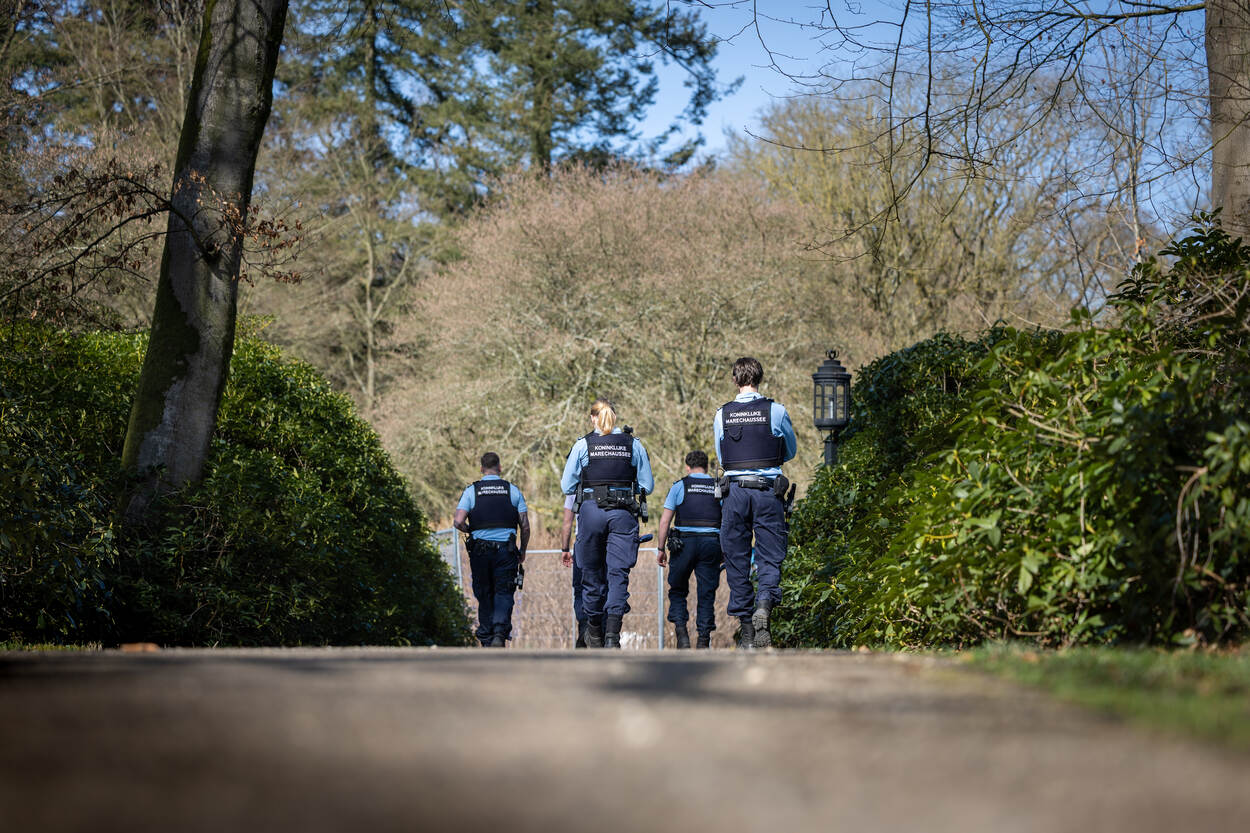 4 militairen van de KMar lopen langs bomen en bosjes.