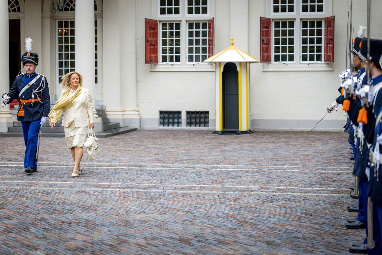 Ambassadeur komt aan bij Palais Noordeinde, geflankeerd door een marechaussee in ceremonieel tenue.
