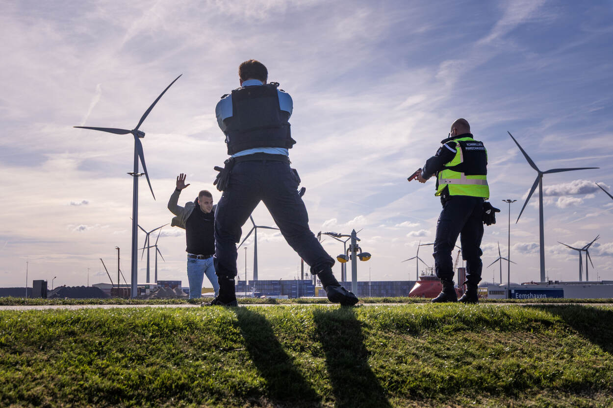 Medewerkers van de marechaussee houden een arrestant onder schot.