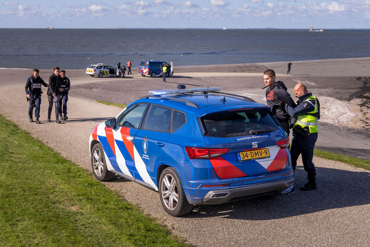Marechaussees brengen twee verdachten in de Eemshaven naar hun voertuig.