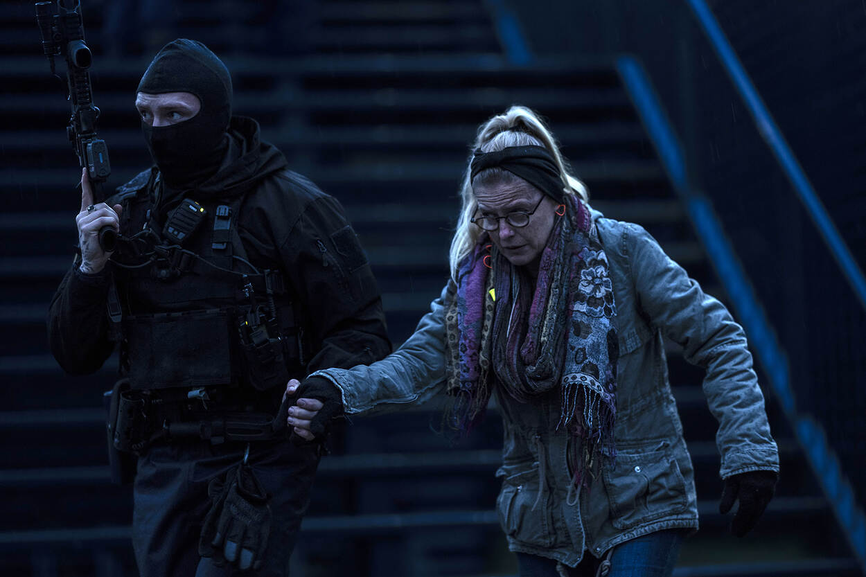 Een GBB’er begeleidt een vrouwelijk slachtoffer van de trap naar buiten.