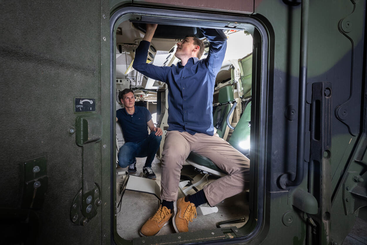 Stagiair Etiën Tax en begeleider Erik van Uem bekijken het interieur van een Boxer pantservoertuig.