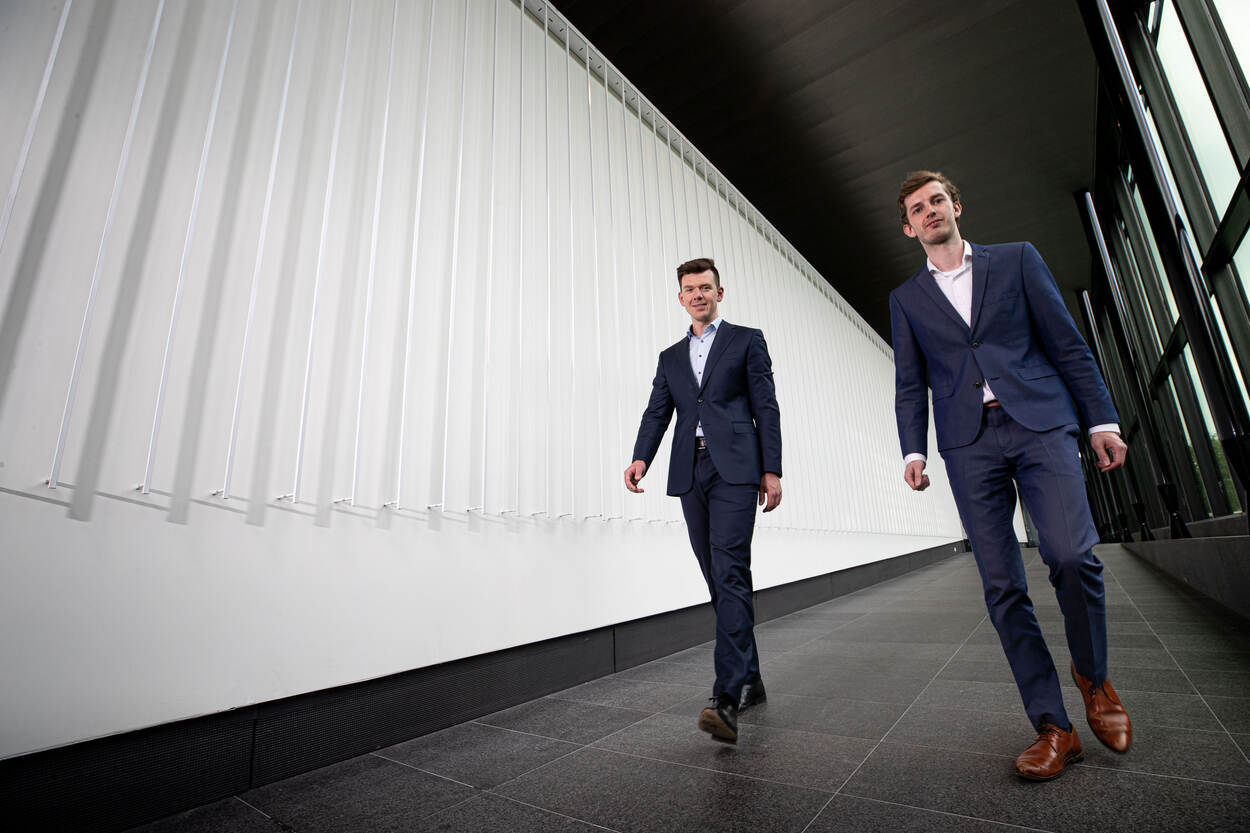 Dennis Neven en Michael Pieper lopen door een gang van het DMO-gebouw.