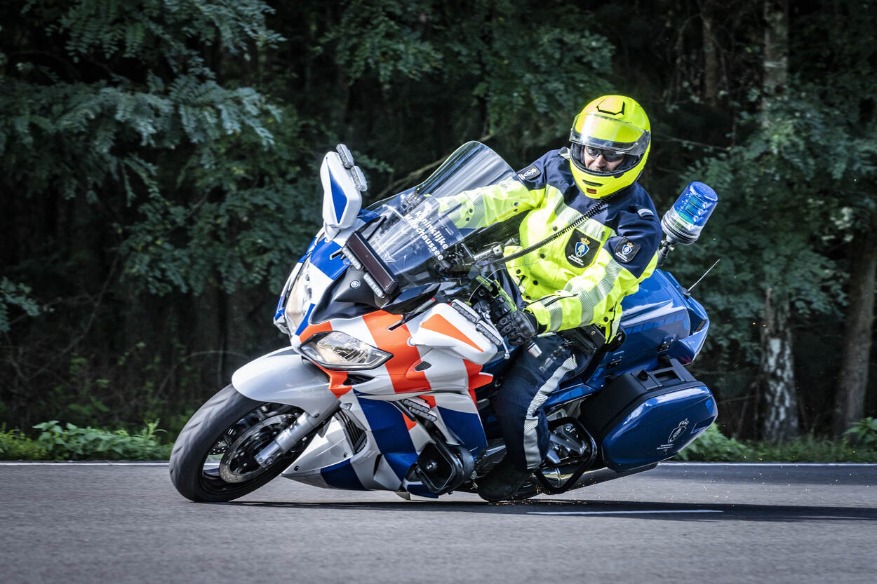 Kmar-motorrijder ligt laag in de bocht op een motor.