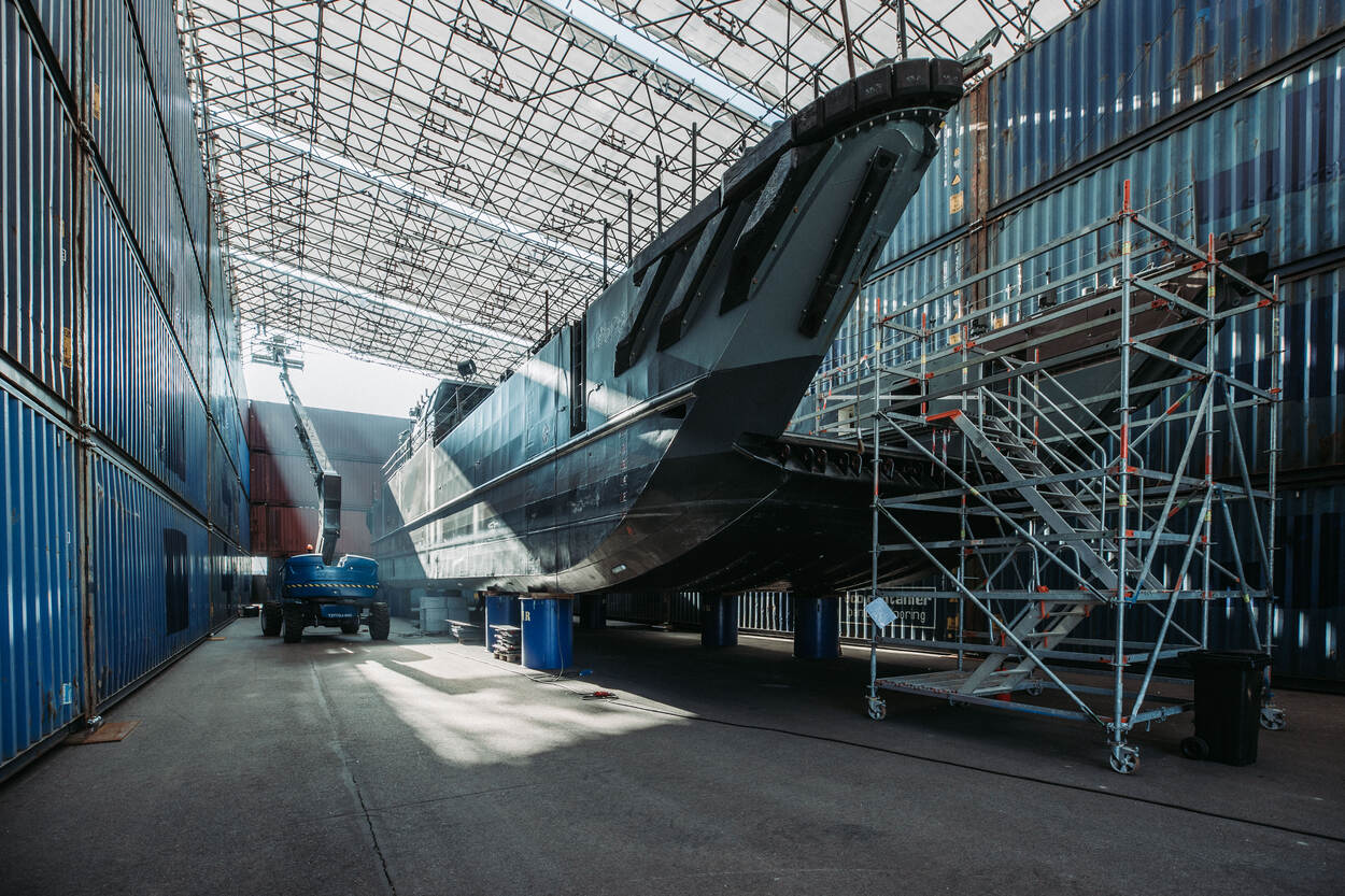 Een Landing Craft Utility in een provisorisch dok met links een hoogwerker. De zon schijnt stemmig in de constructie.