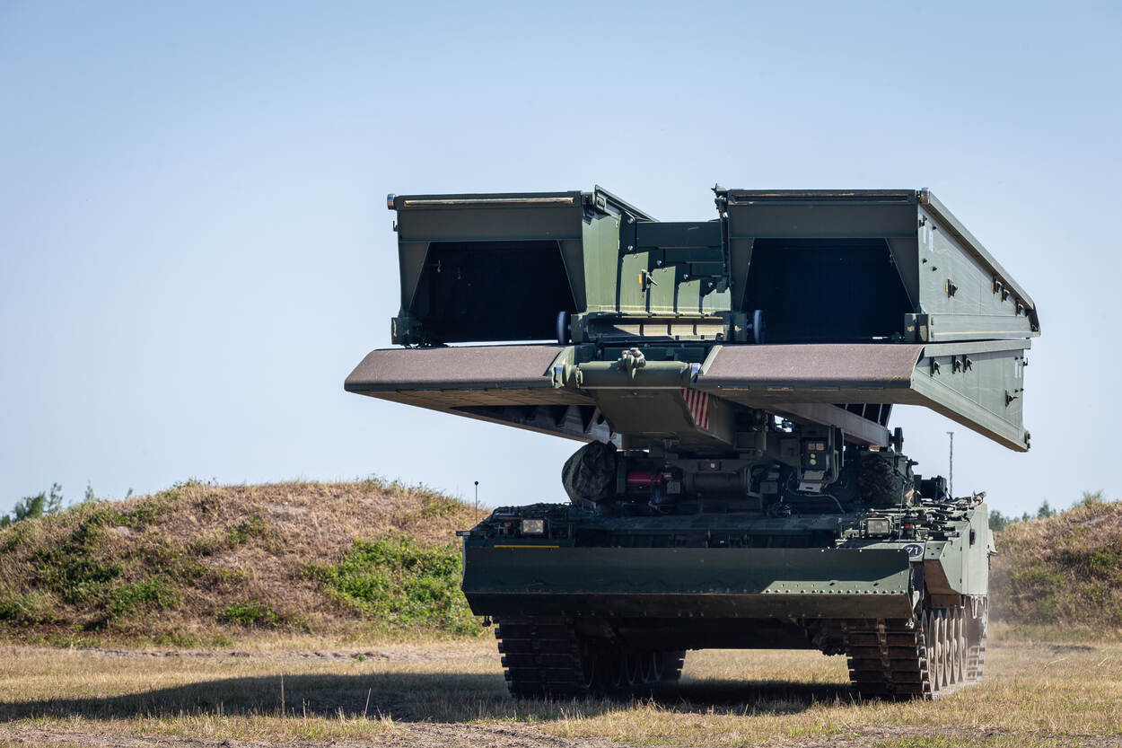 Leguaan bruglegger met enkele heuveltjes erachter.