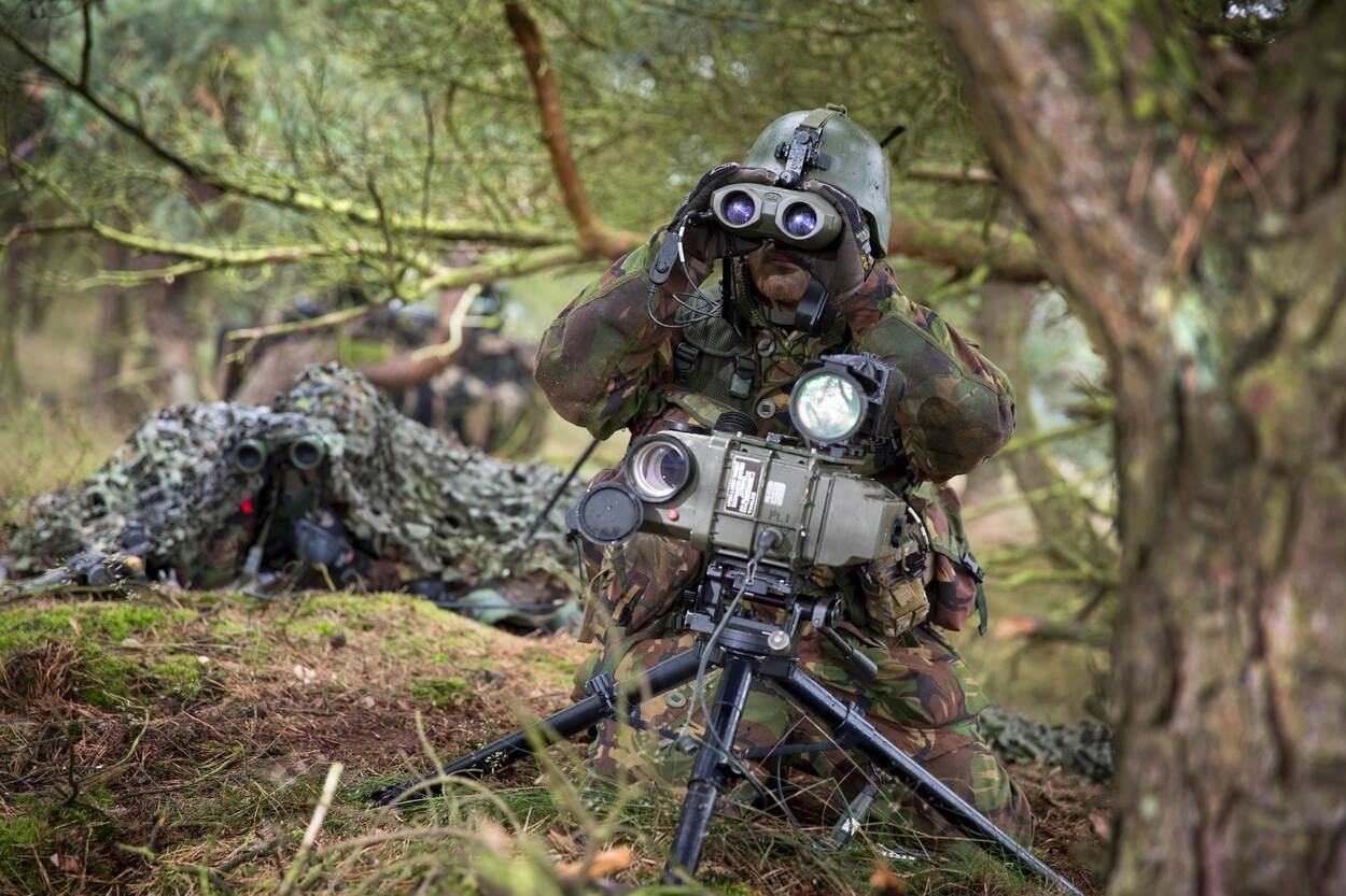 Een militair met optische middelen in het struikgewas.