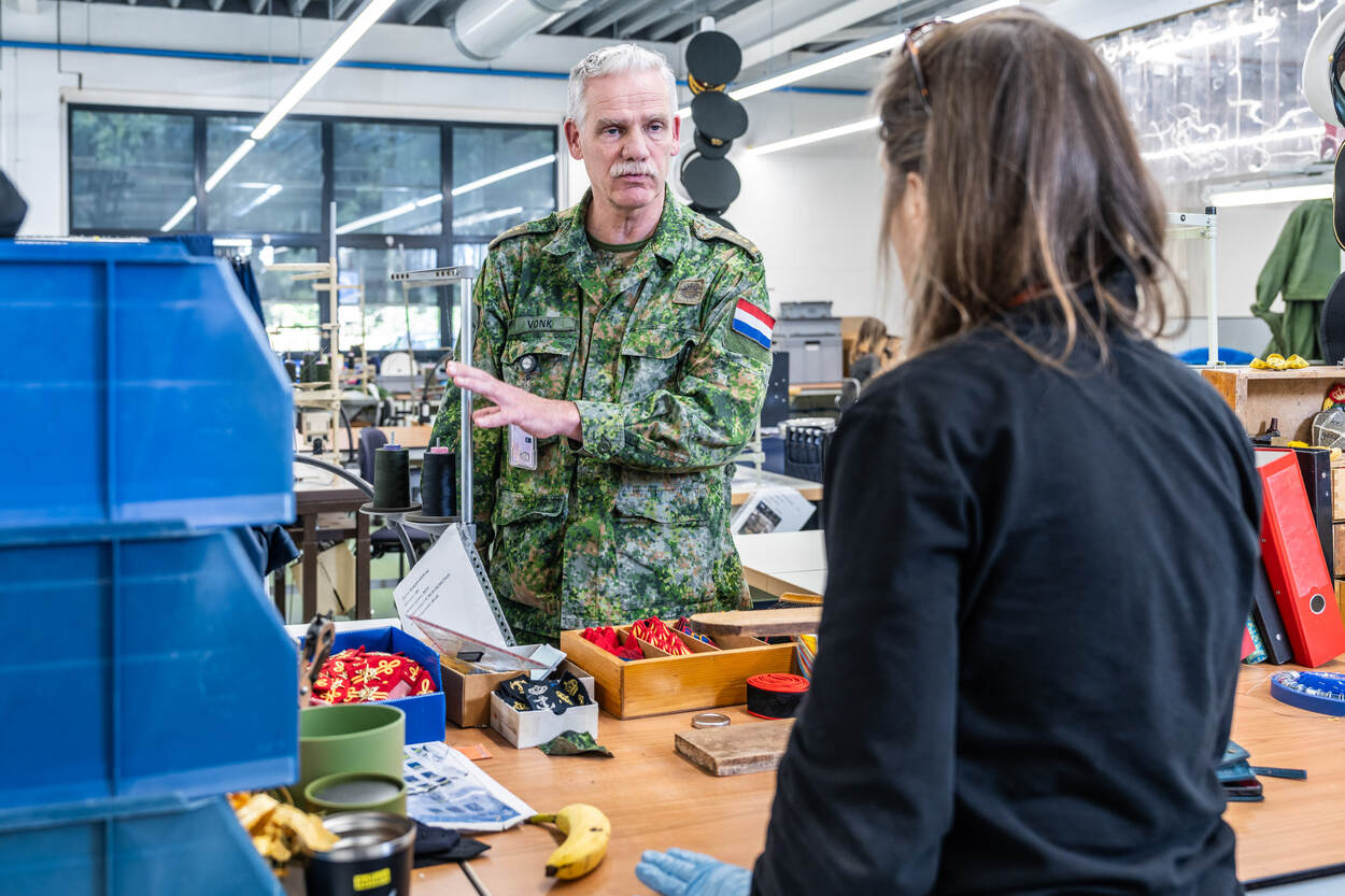 Commandant KPU-bedrijf kolonel Jan Vonk voor een werkbank met een medewerker.
