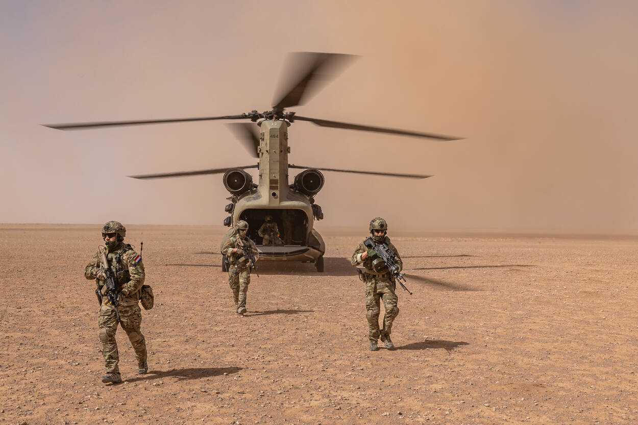 Uitgestegen militairen bij een Chinook in een zandomgeving in Irak.