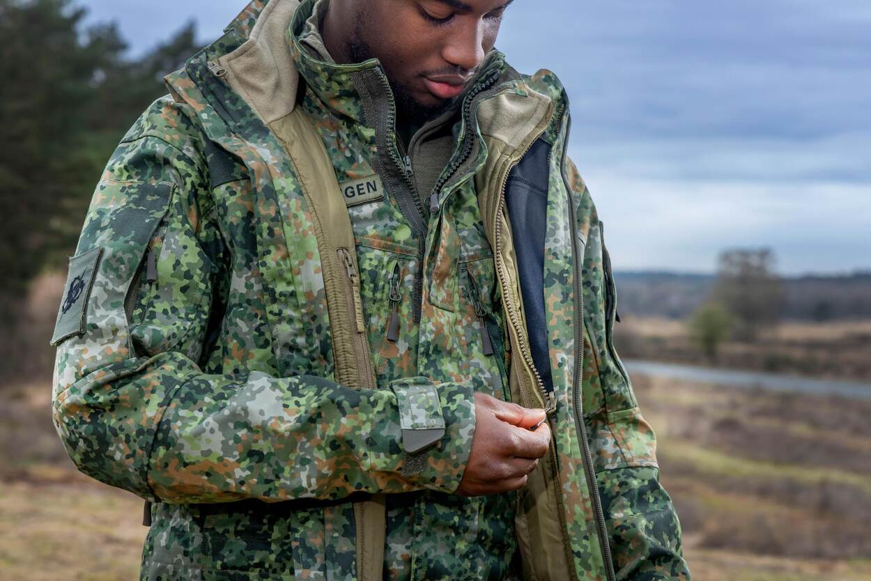 Een militair laat de binnenzijde van zijn jas zien.