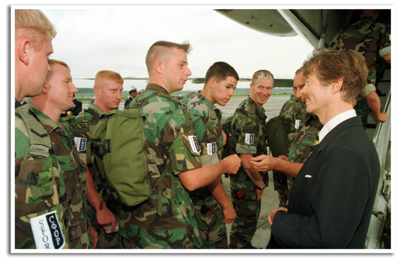 Minister van Defensie Joris Voorhoeve geeft een boks aan een marinier die een vliegtuig instapt op weg Bosnië.