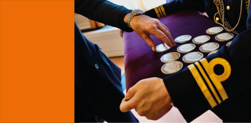 Close-up van militair die kussen vol herinneringsmunten vasthoudt. 