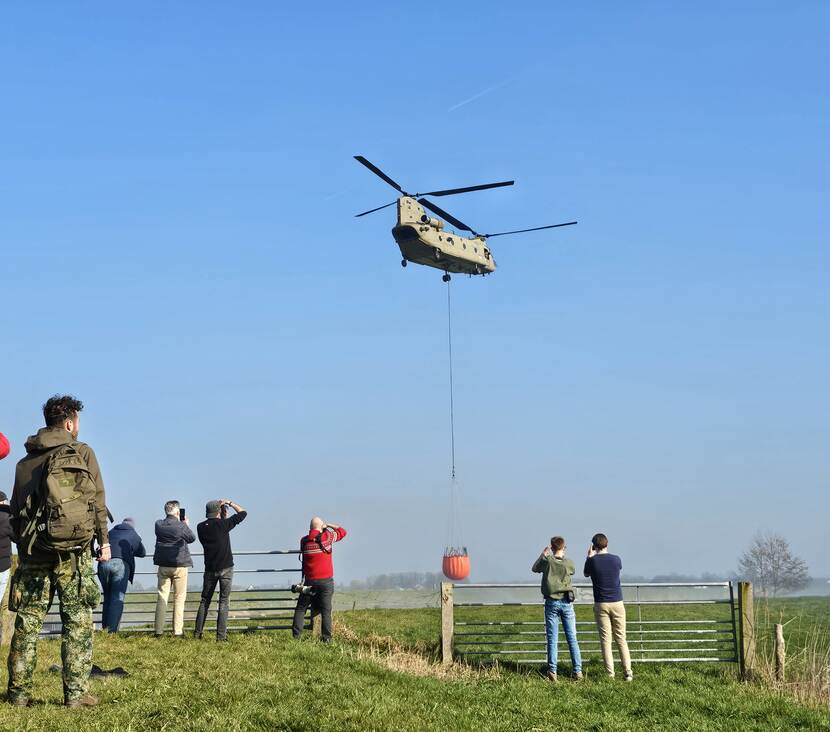 Een Chinook transporthelikopter haalt water in de Eem met een bucket.
