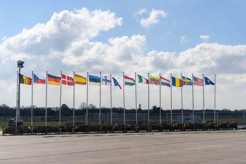 Een zestiental vlaggen wappert naast elkaar. Aan het einde de NAVO-vlag.