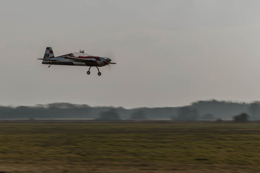 Een radiografisch vliegtuig vliegt net boven de landingsbaan.
