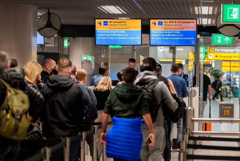 Een rij passagiers wacht bij de paspoortcontroles op Schiphol.