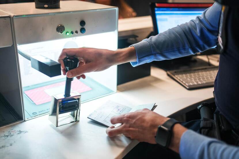 een marechaussee stempelt een paspoort.