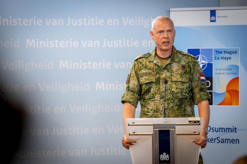 Militair staat achter katheder.