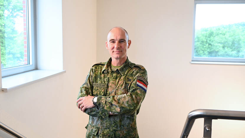Portret van militair in uniform met armen over elkaar.