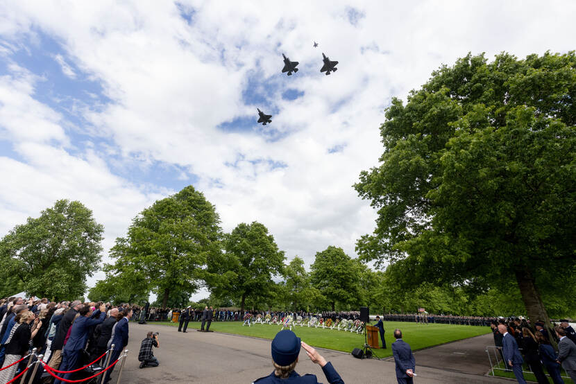 Aanwezigen kijken tijdens de herdenking in Margraten naar de lucht waar straaljagers overvliegen.