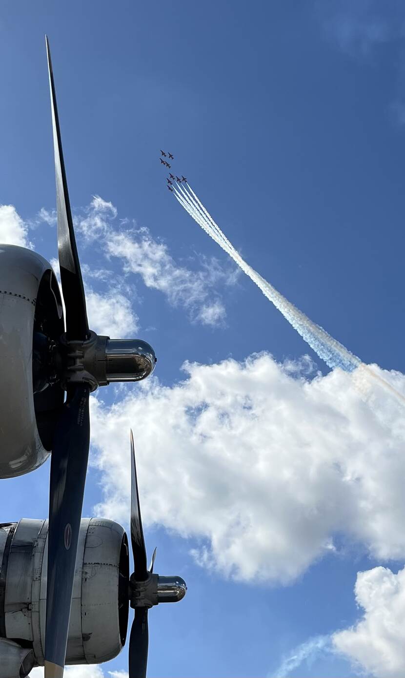 In de verte negen vliegtuigen dichtbij elkaar, op de voorgrond propellers van een vliegtuig.