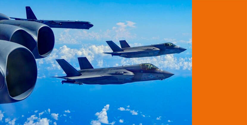 Twee straaljagers en een groot militair vliegtuig, een B-52, vliegen hoog boven de wolken, met de vier enorme motoren van een tweede B-52 op de voorgrond.