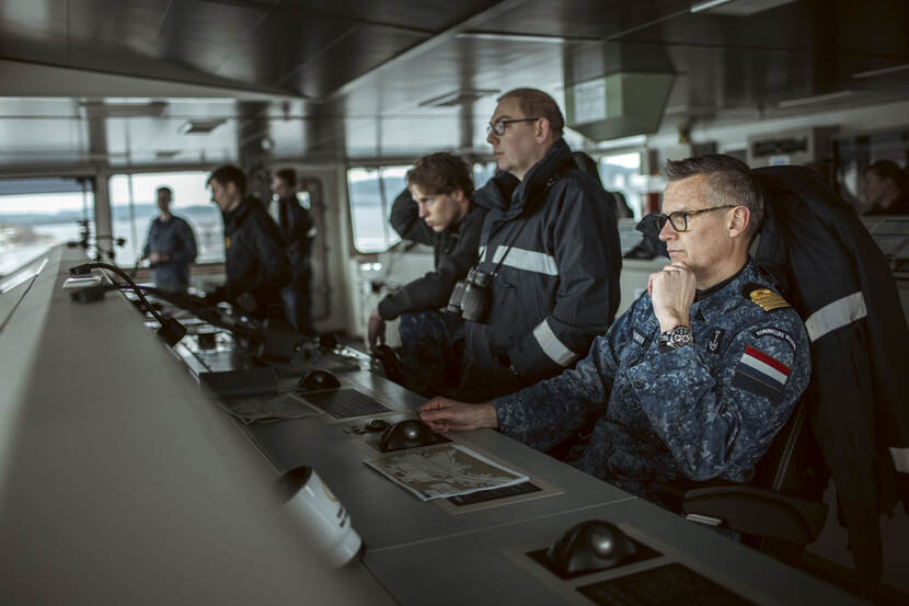 De commandant van Zr.Ms. Johan de Witt kijkt geconcentreerd over zee vanaf de brug.