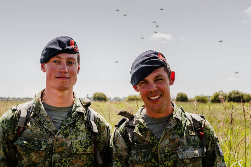 Foto van eerste luitenant der mariniers Maarten en majoor der mariniers Wim Roelink met op de achtergrond landende parachutes.