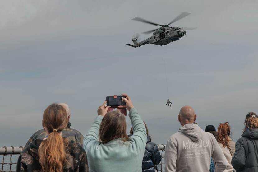 Een rescue operator hangt aan een hoist-kabel onder de NH90-maritieme gevechtshelikopter.