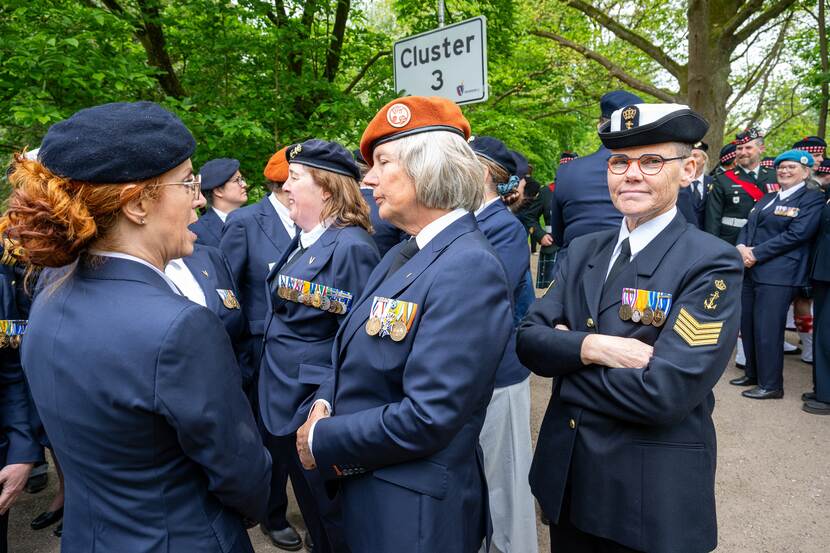 Een aantal leden van Ex-act verzamelen bij het bord Cluster III in een park in Wageningen.
