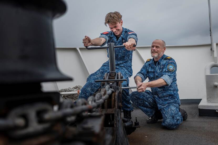 Een adelborst die onder toezicht de ankerketting bedient.