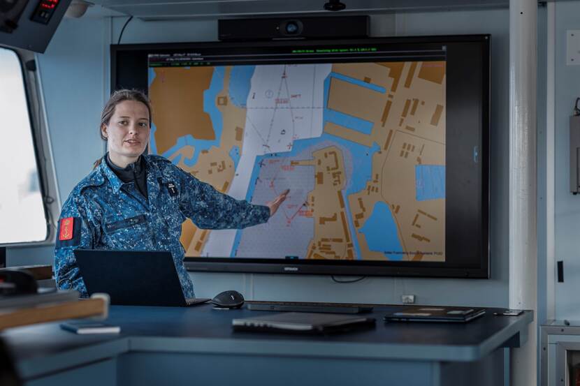 Een vrouwelijke adelborst legt haar vaarplan voor aan haar collega’s.