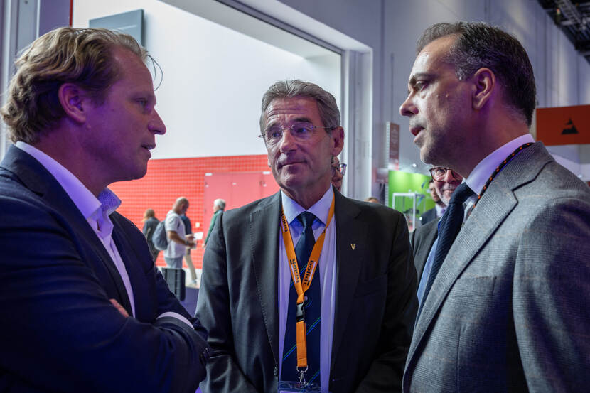 3 mannen in pak, staatssecretaris Tuinman en Huub Geilenkirchen (midden) en Robert van Aarle van Bolidt, spreken met elkaar.
