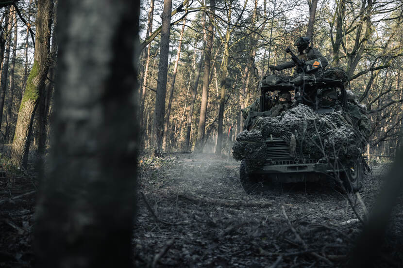 Een voertuig rijdt door het bos.