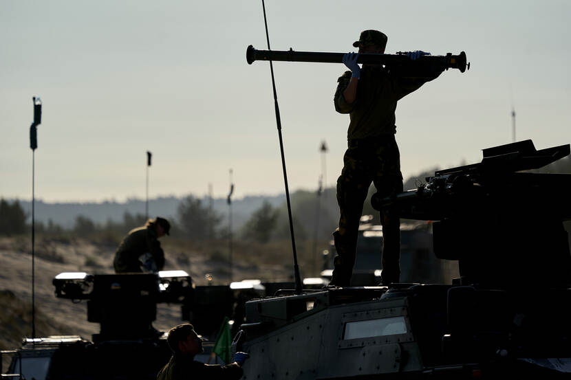 Silhouet van een militair die een Stinger installeert op een Fennek verkenningsvoertuig.