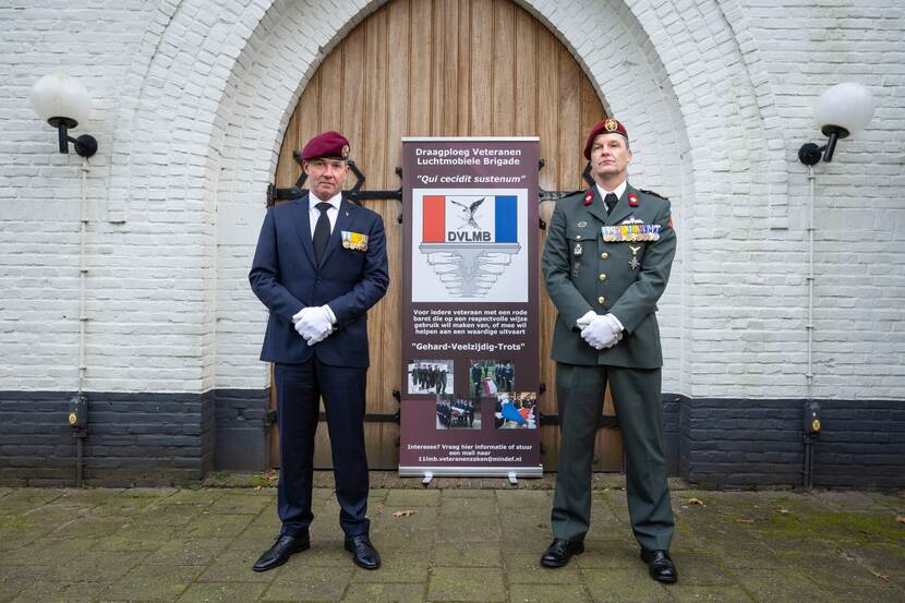 Veteraan Henk Tukker (links) en sergeant-majoor Patrick de Groot voor de banner van de draagploeg, buiten voor de Witte Kapel.