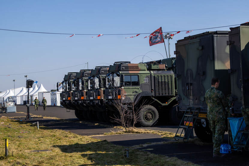 Het oefenterrein op de vliegstrip met witte tenten en voertuigen.