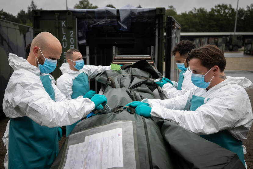 Vier militairen bij een lijkzak.