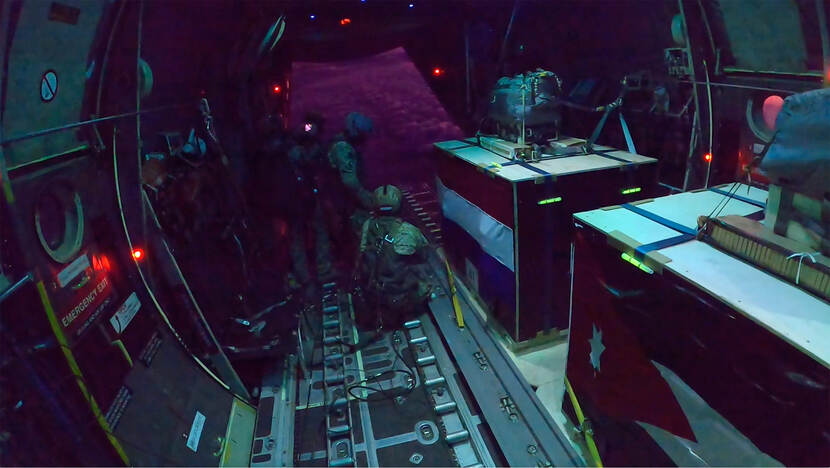 Nederlandse militairen met bundels hulpgoederen in de C-130 vlak voordat er gedropt gaat worden.