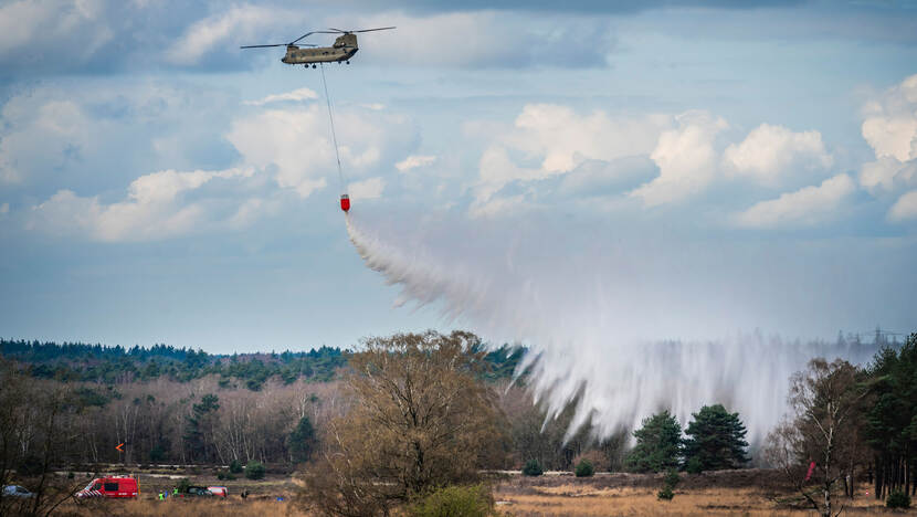 Een Chinook blust met een bluszak een fictieve brand in het bos.