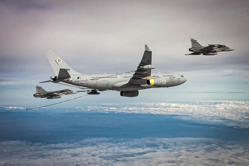 twee Saab Gripens vliegen naast een A330 MRTT om in de lucht te tanken.