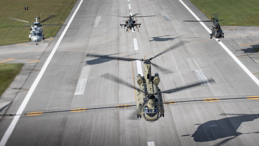 Een Apache, Chinook, Cougar en NH90 hoveren boven een startbaan.