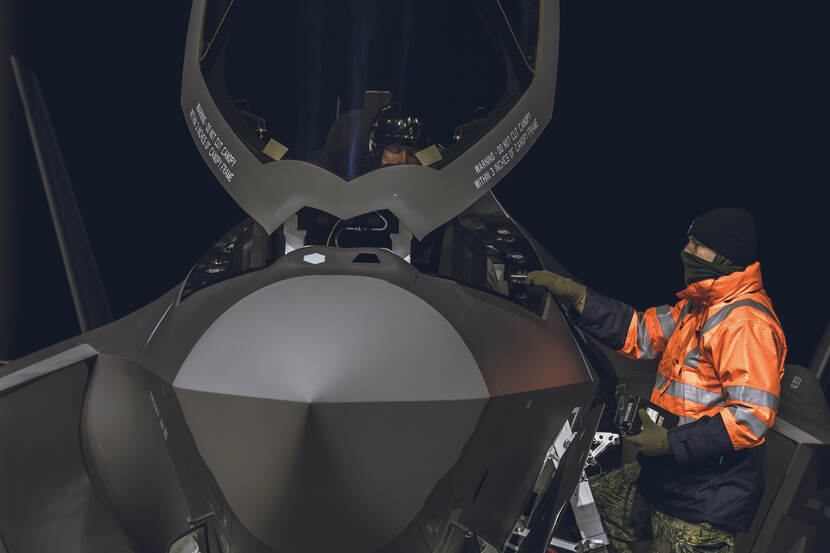 Vlieger in F-35 cockpit, techneut staat er op een trap naast.