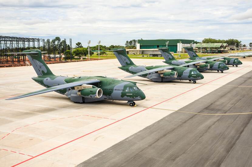 Vier groen-grijs gecamoufleerde Braziliaanse C-390’s naast elkaar op een flightline.