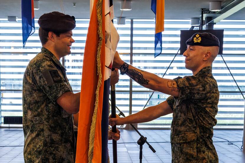 Luitenant-kolonel Sam de Haas overhandigt een vlag aan majoor Thom Brand.