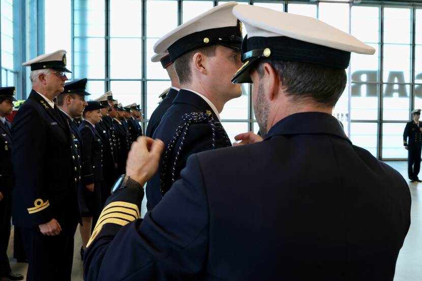 Marineman brengt erekoord om schouder aan.