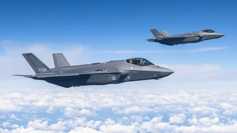Twee F-35 jachtvliegtuigen naast elkaar in de lucht.