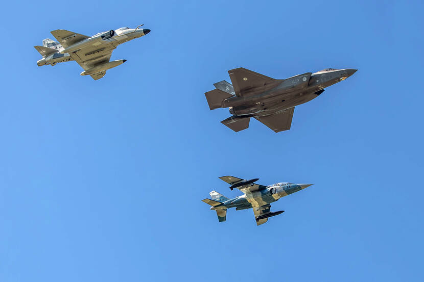 Een F-35 vliegt met links een A-4 en rechts een Alpha Jet, van onderaf gezien tegen een blauwe lucht.