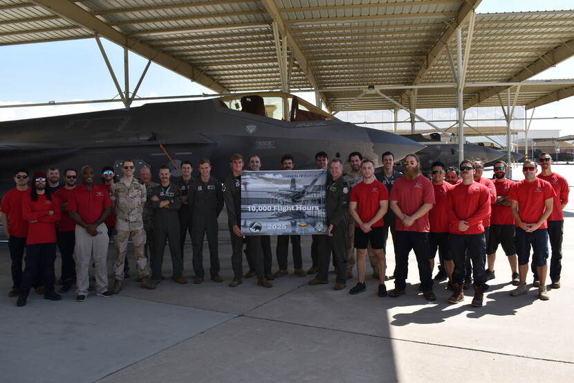 Grote groep mensen met een bord ‘10.000 Flight Hours’, achter hen een F-35.