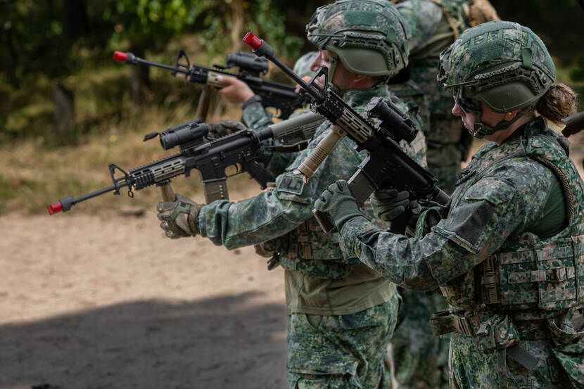 Militairen in het bos met lange wapens.